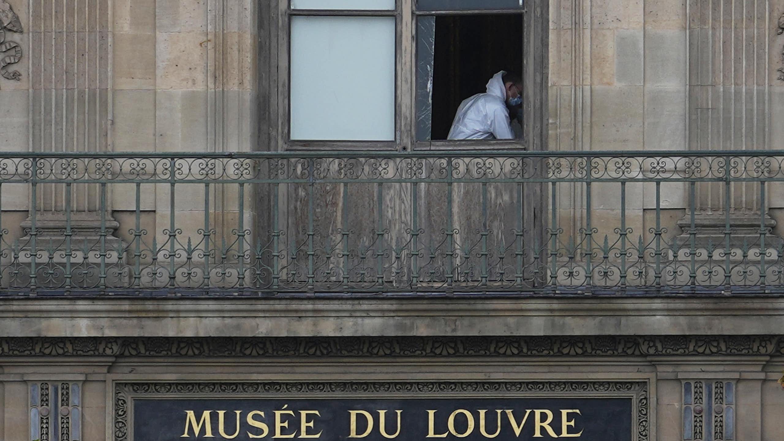 A man in white overalls through a broken window.