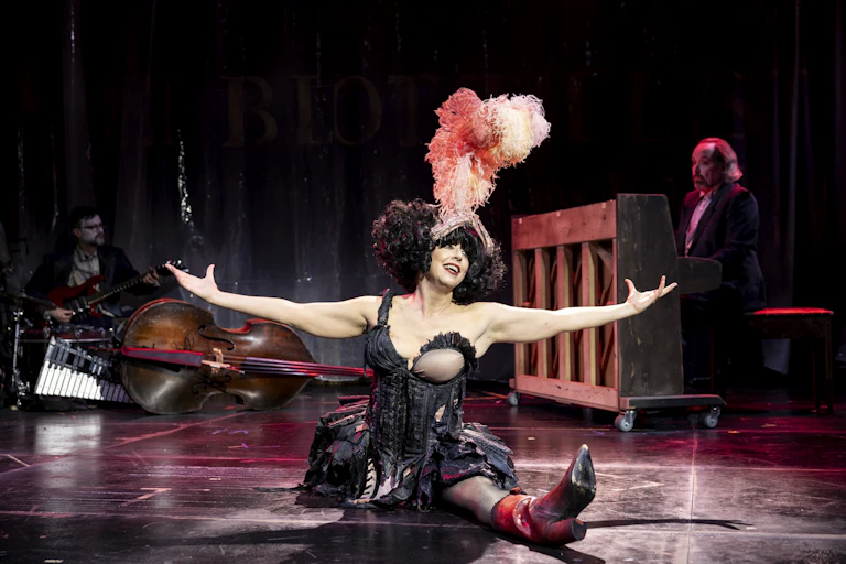 Meow Meow in the splits wearing a feather headdress.