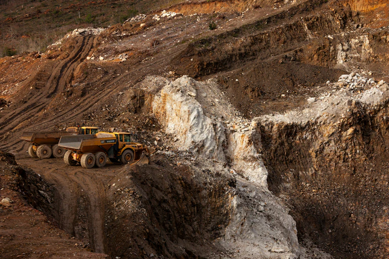 A couple of mining dump tricks parked on a rubble-strewn hillside