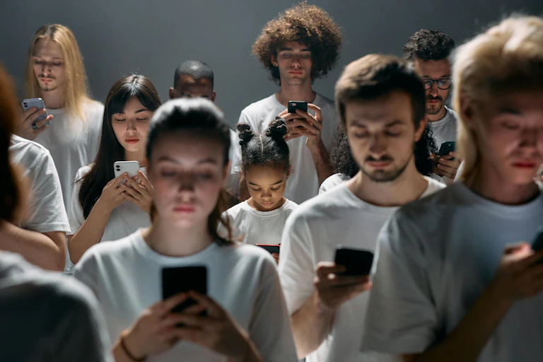 Des jeunes avec des tee-shirts blancs en train de regarder des smartphones.
