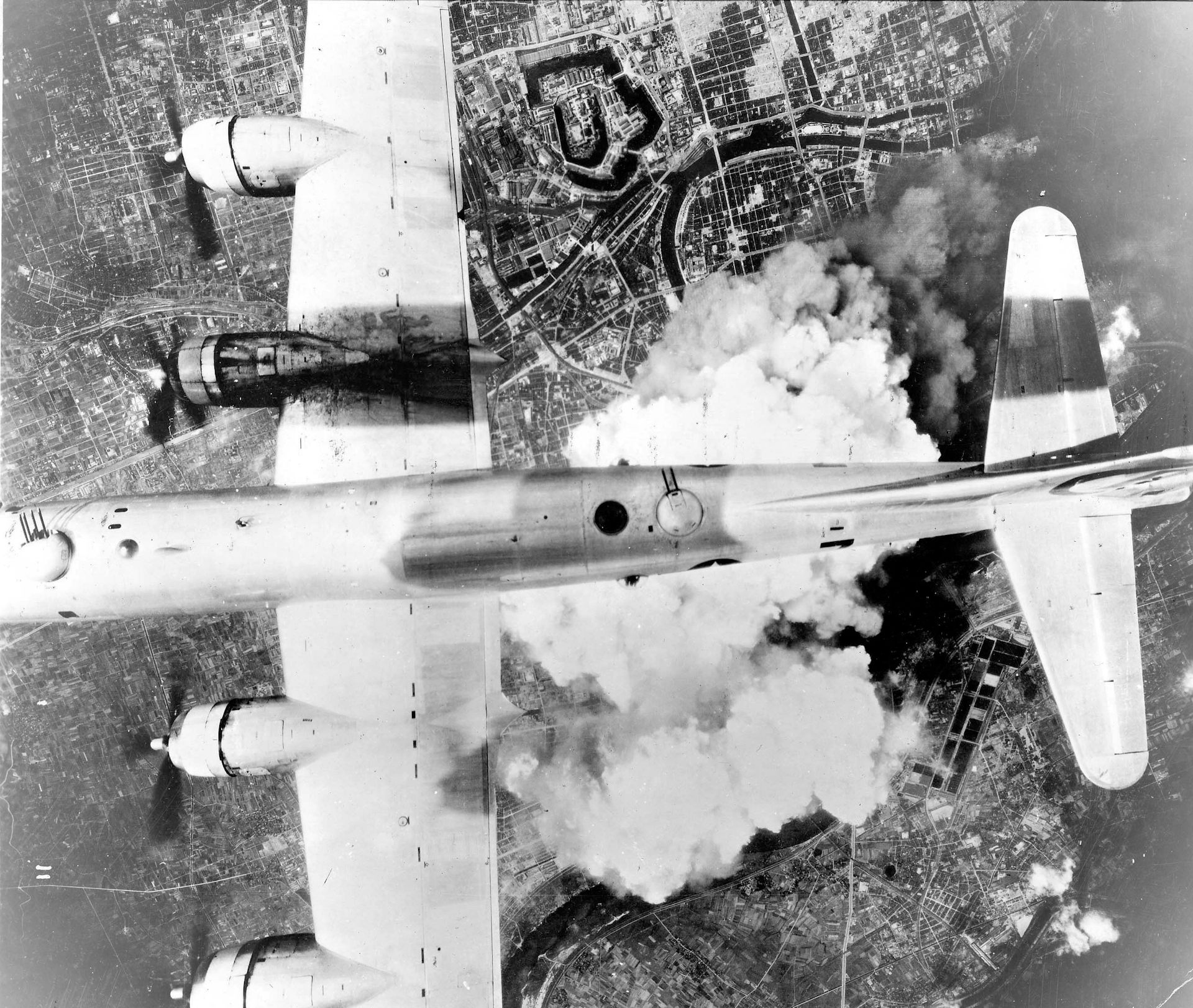Black and white photo of a plane flying over clouds