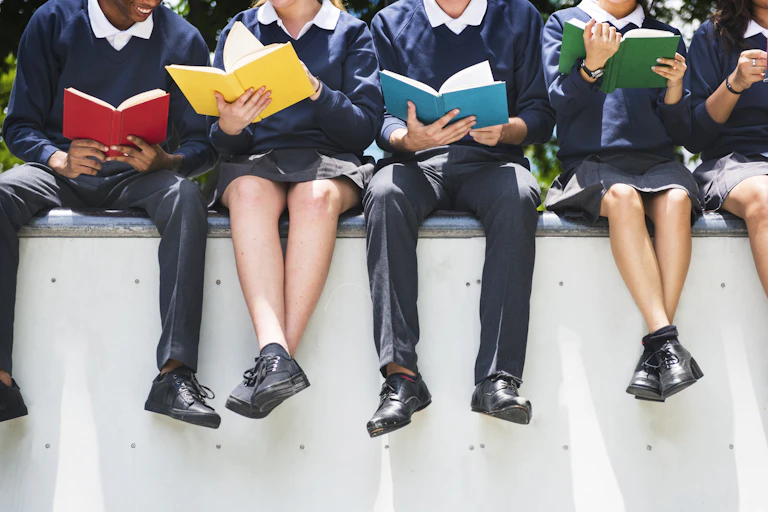 Teenagers sat on wall reading books