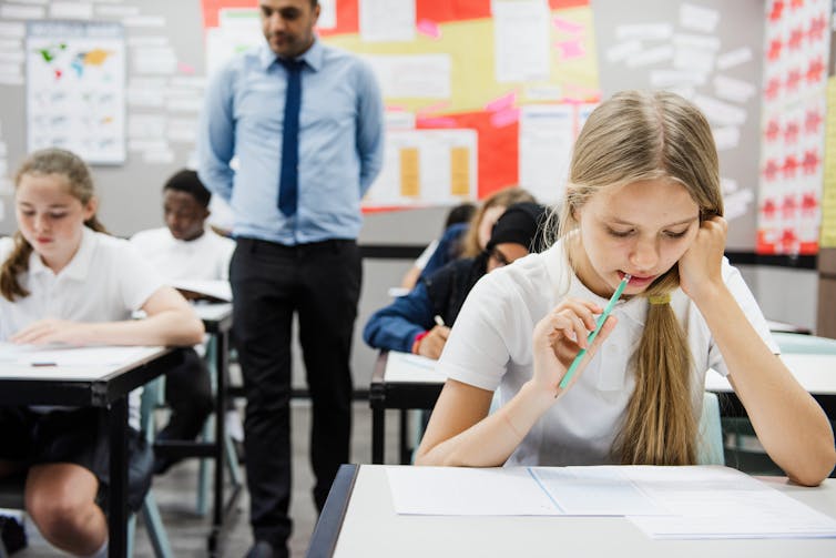 Teenagers in uniform sitting a classroom test