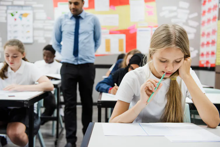 Teenagers in uniform sitting a classroom test