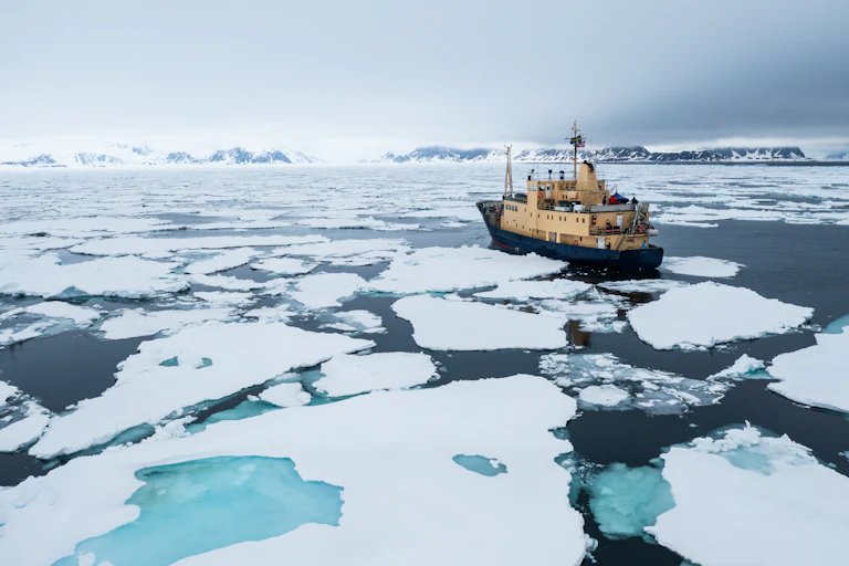 Barco navega en un océano cubierto de placas de hielo