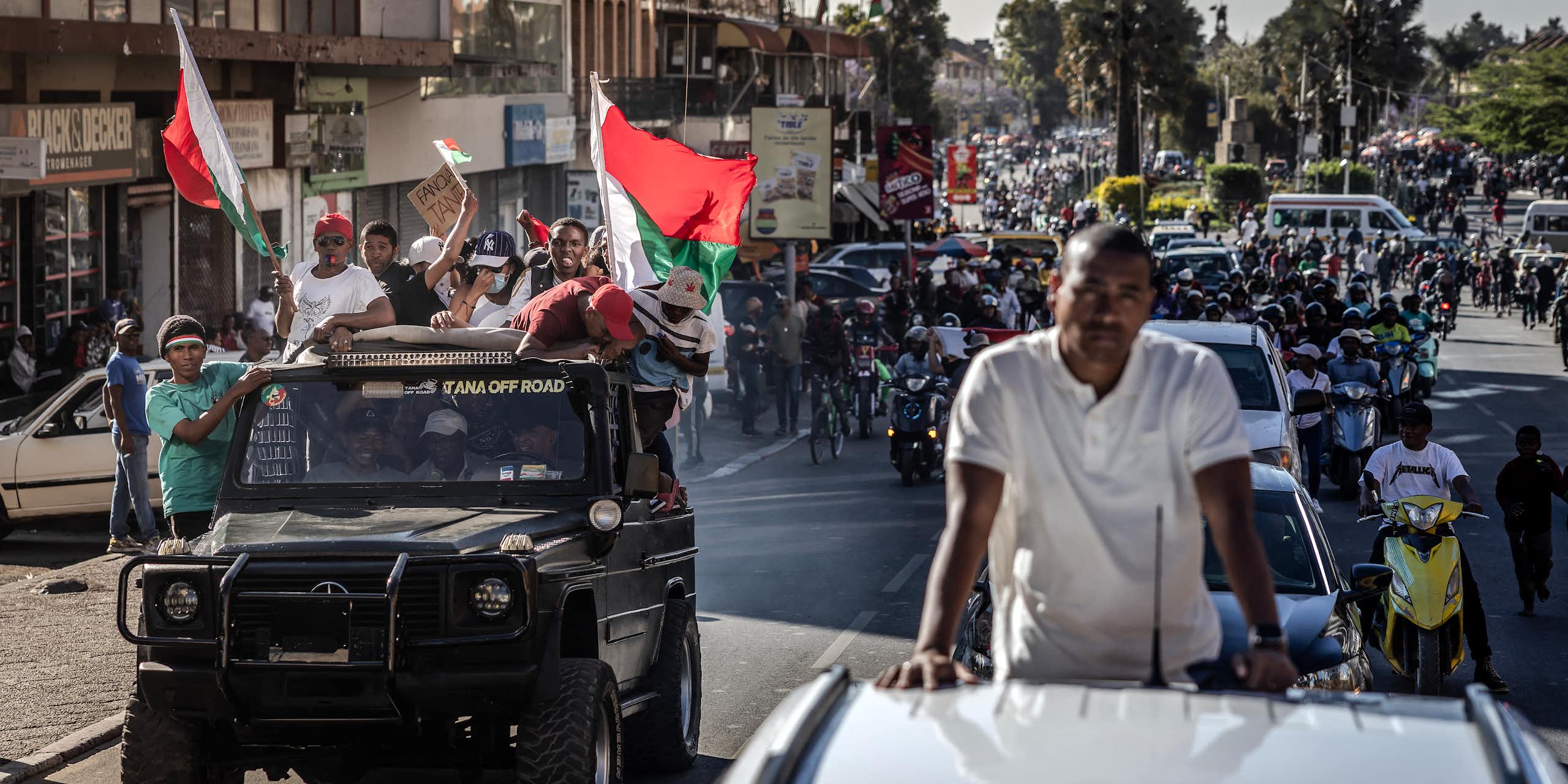 People waving Malagasy flags and singing while following soldiers on the streets