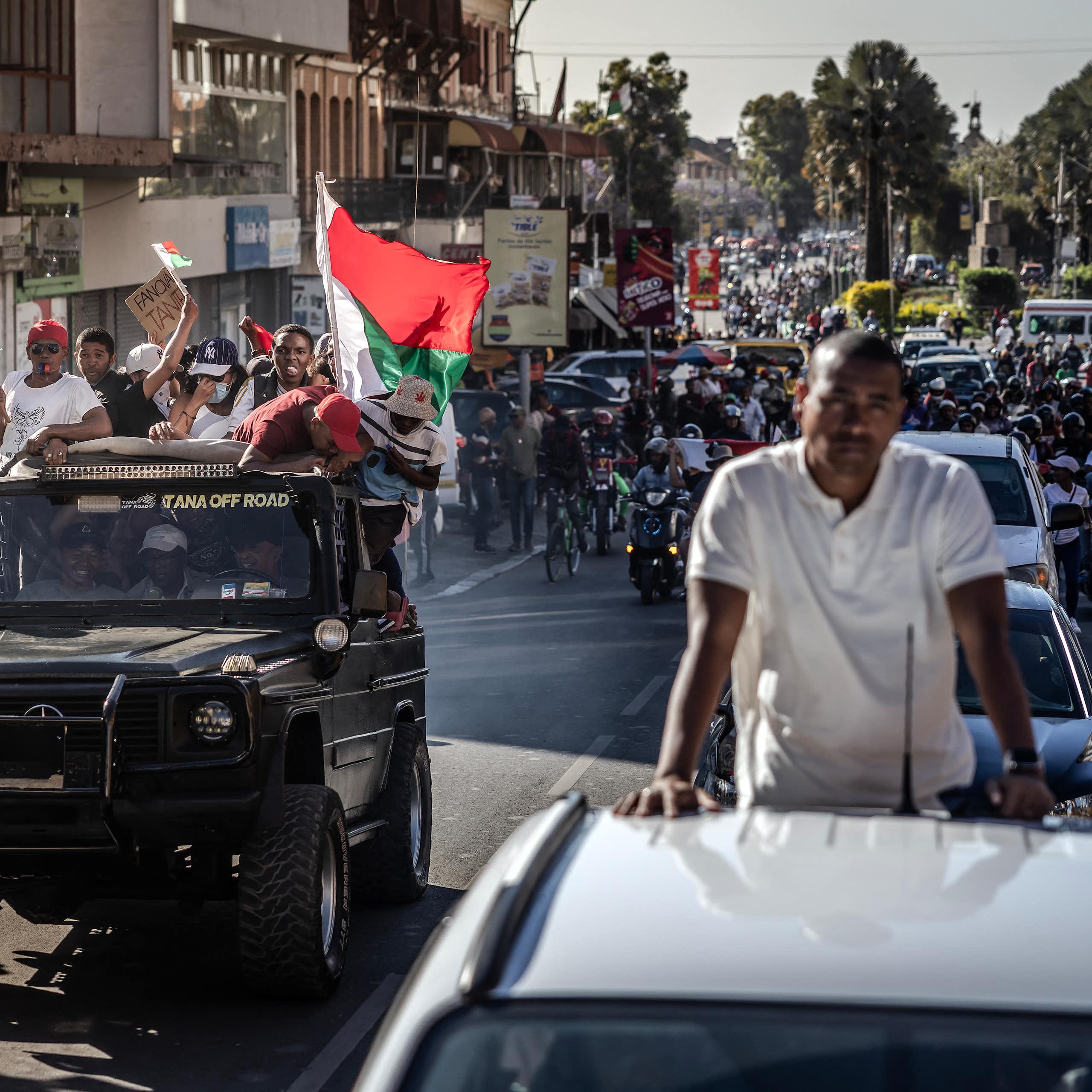 People waving Malagasy flags and singing while following soldiers on the streets