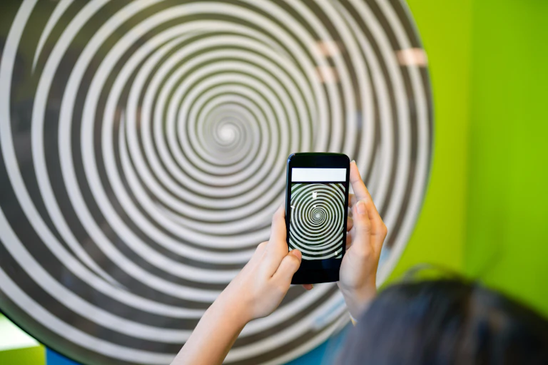 Une adolescente tenant un smartphone qui représente une spirale.