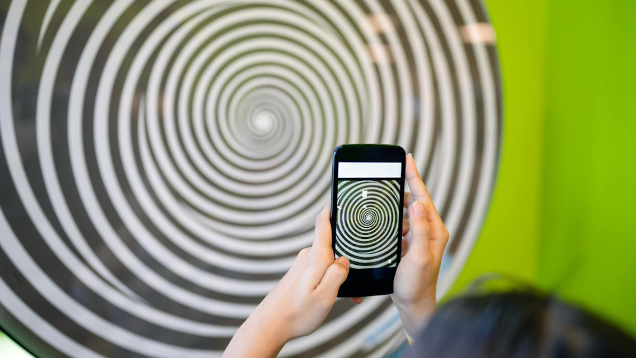 Une adolescente tenant un smartphone qui représente une spirale.