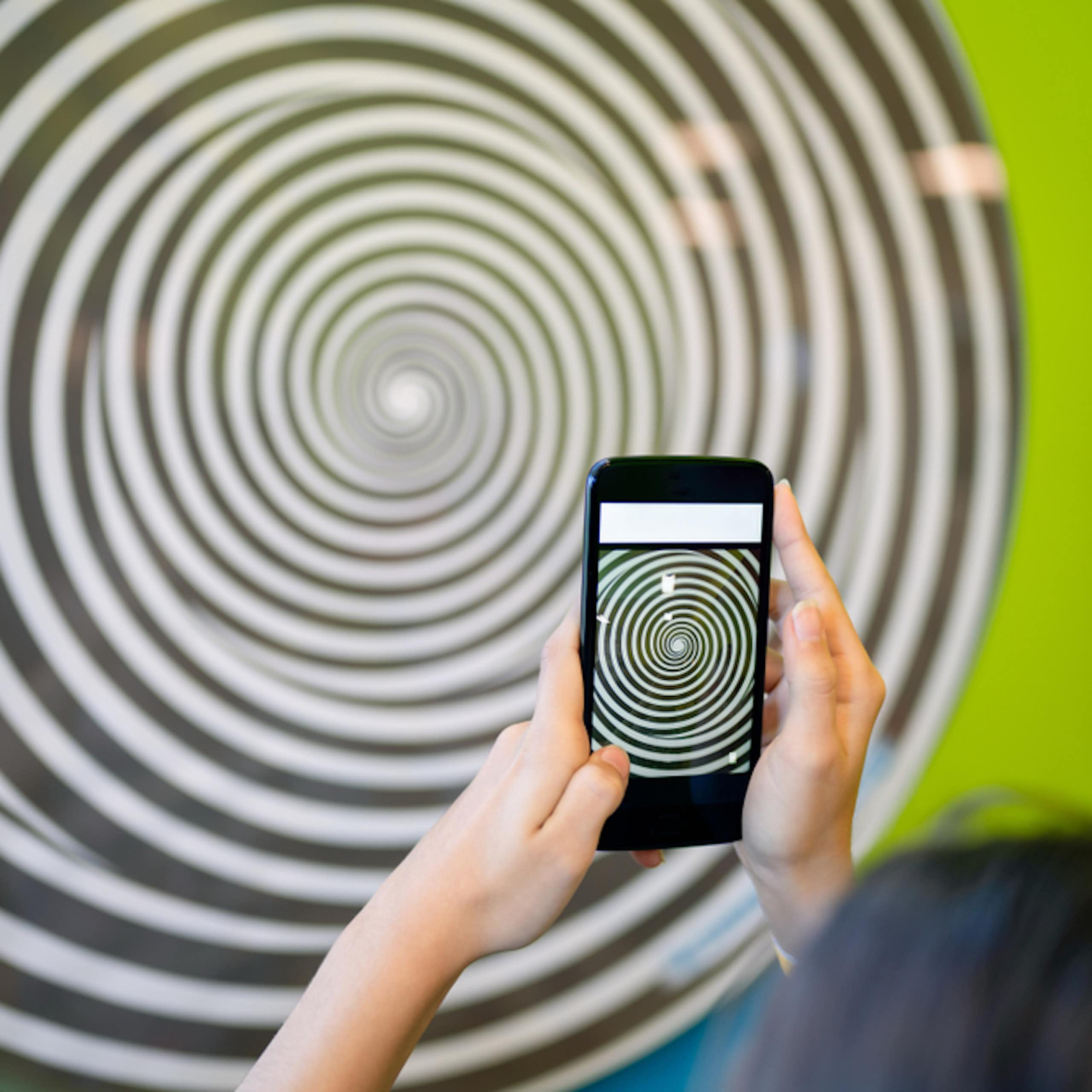 Une adolescente tenant un smartphone qui représente une spirale.