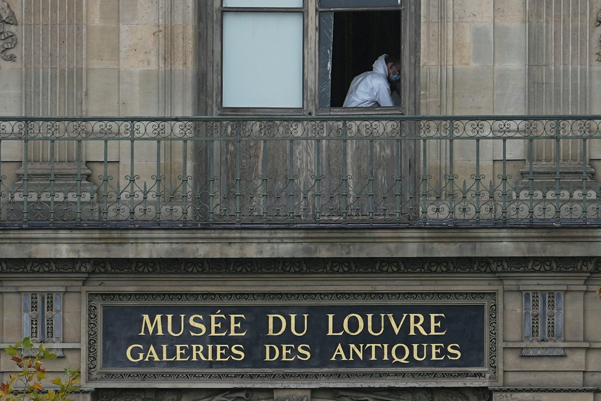 A man in white overalls through a broken window.