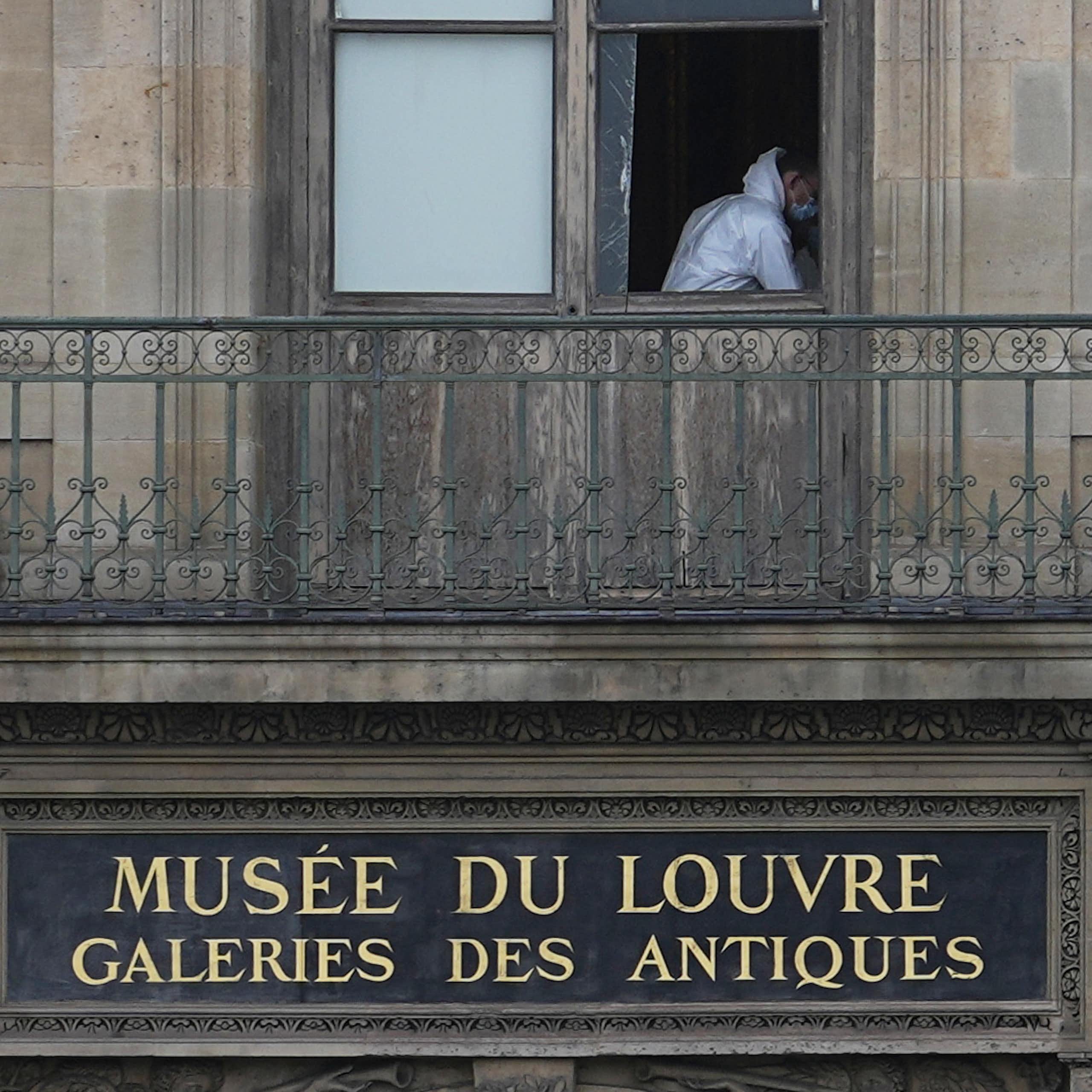 A man in white overalls through a broken window.