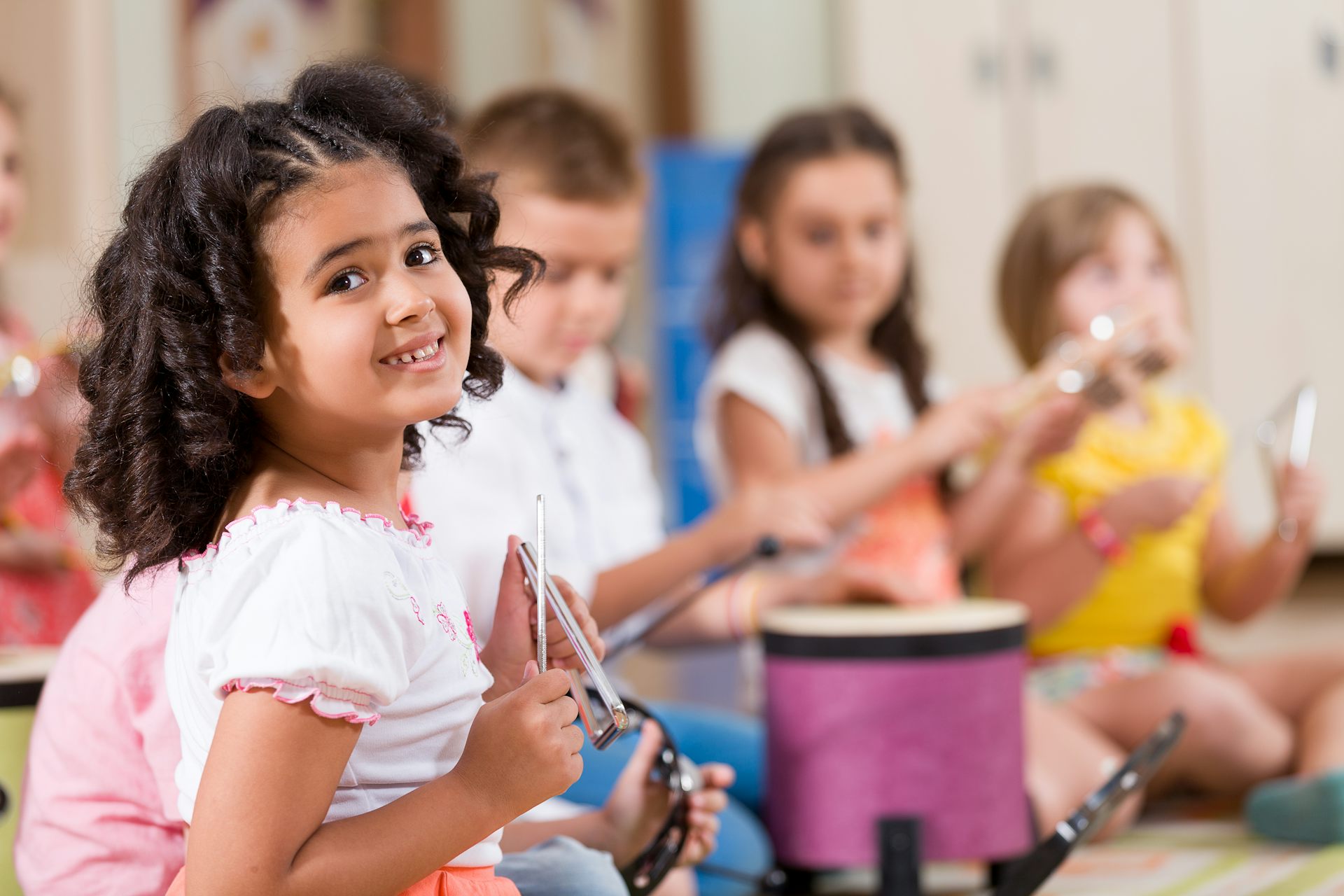 Niños tocando instrumentos de percusión en una clase.