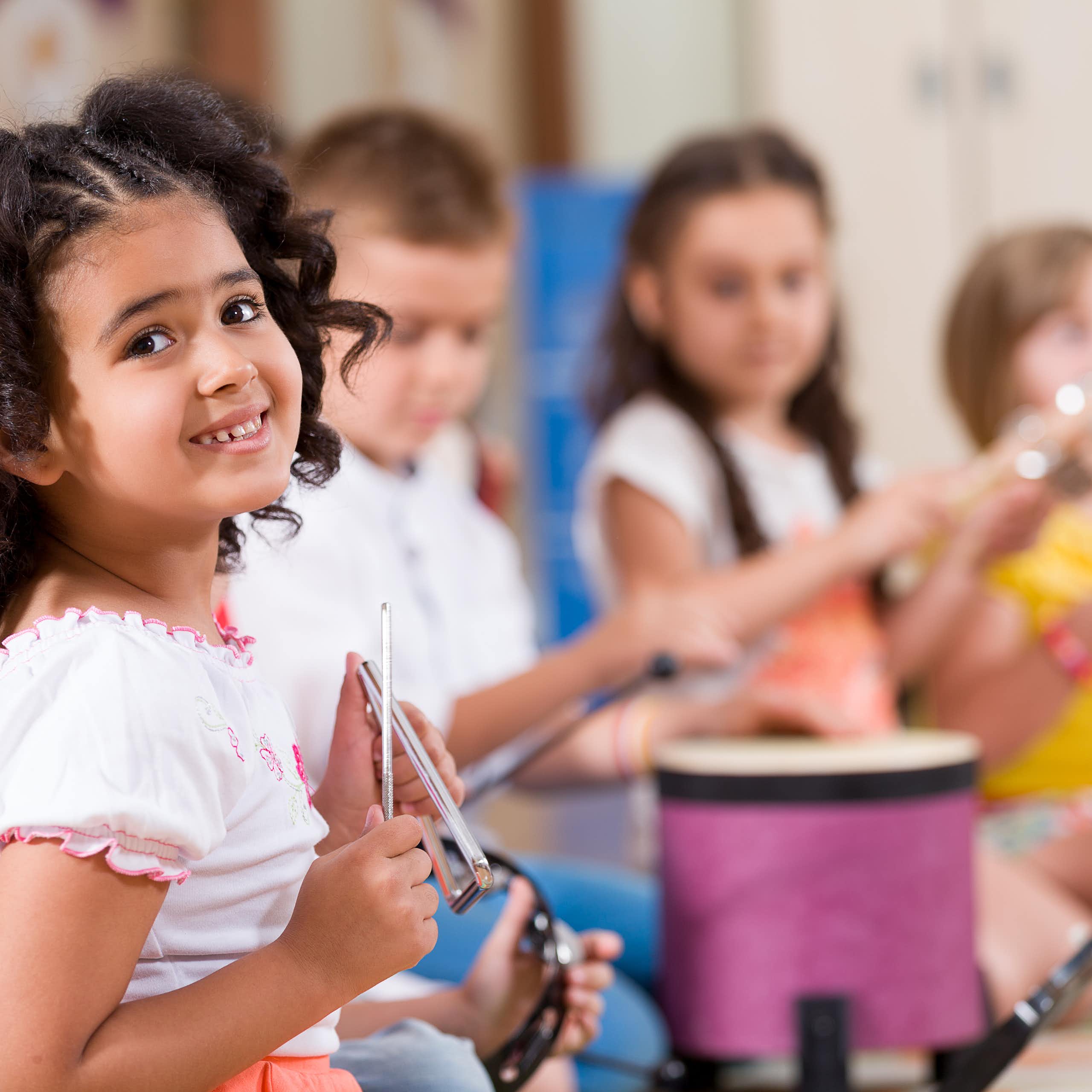 Niños tocando instrumentos de percusión en una clase.