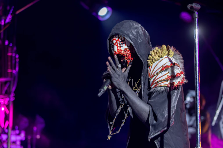 Man performing wearign a thick white mask and hood.