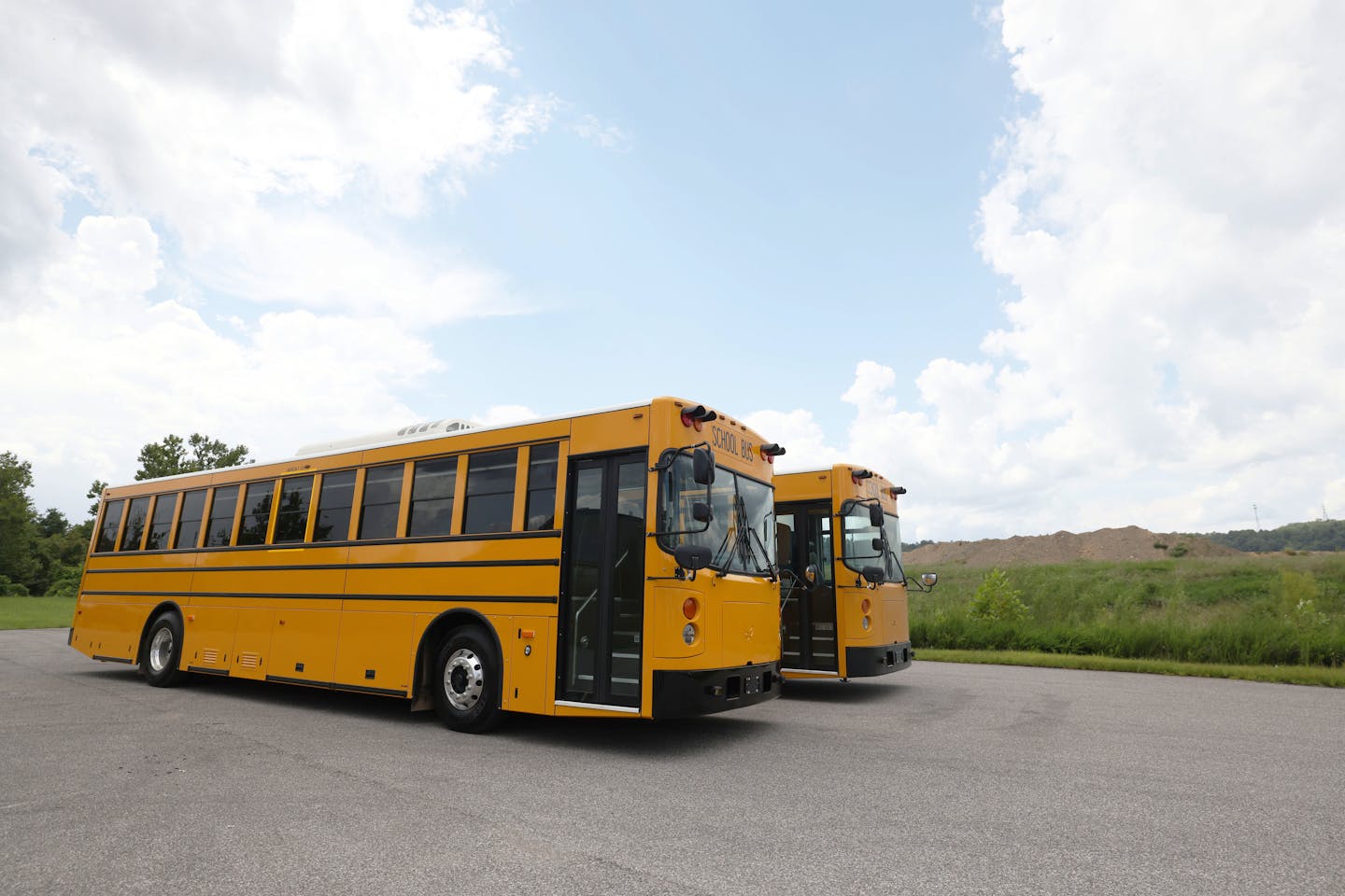 Two large yellow buses are parked next to each other.