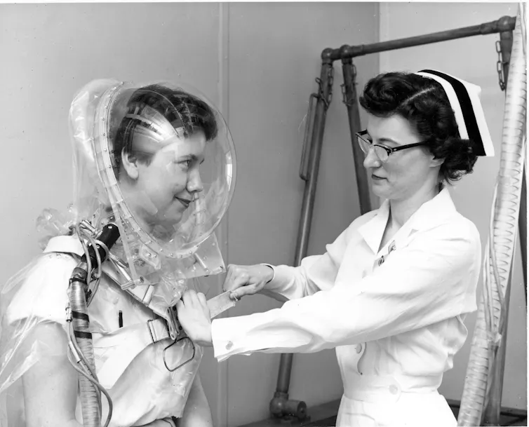 A nurse fits a study volunteer with a clear plastic hood.