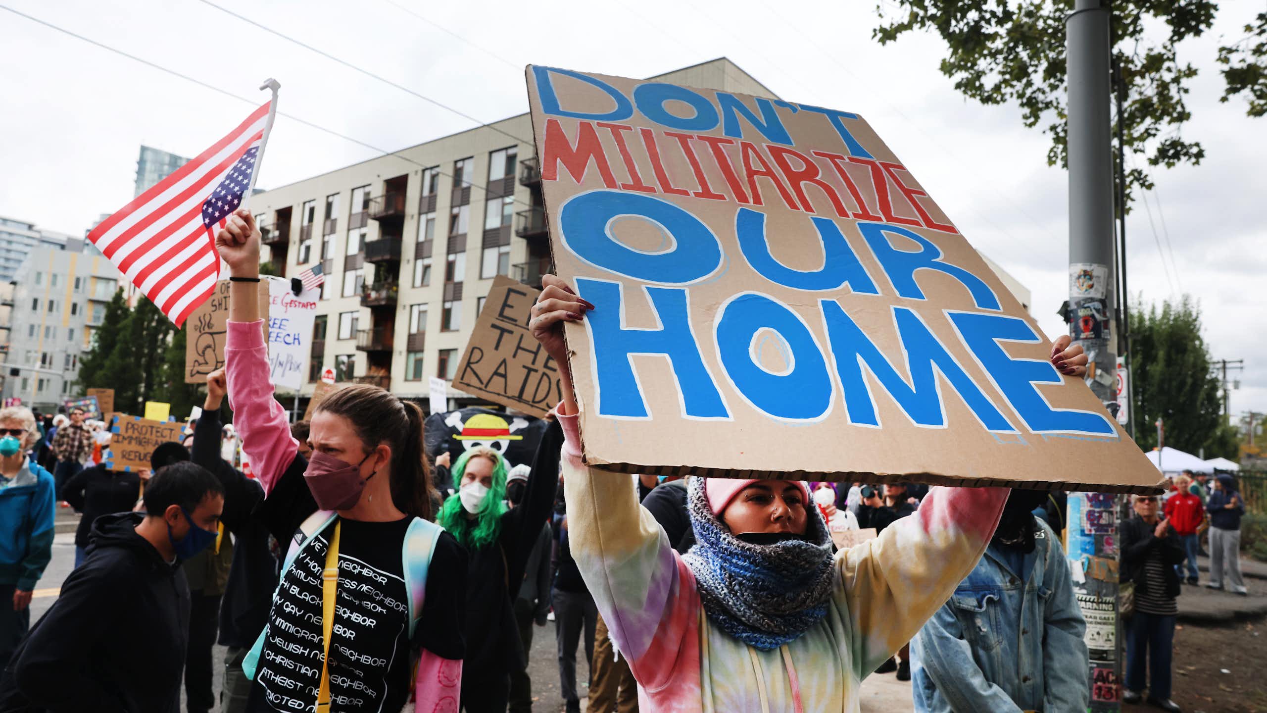 A protester with a sign 'DON'T MILITARIZE OUR HOME.'