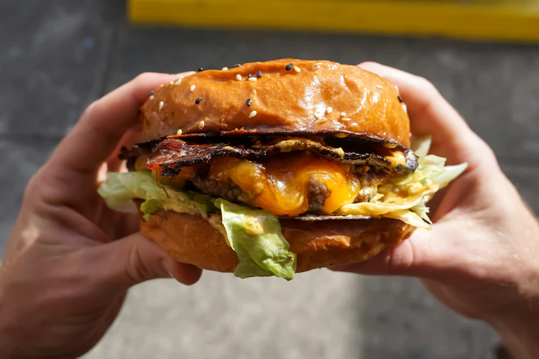 Close-up of a juice burger with bacon and runny egg.