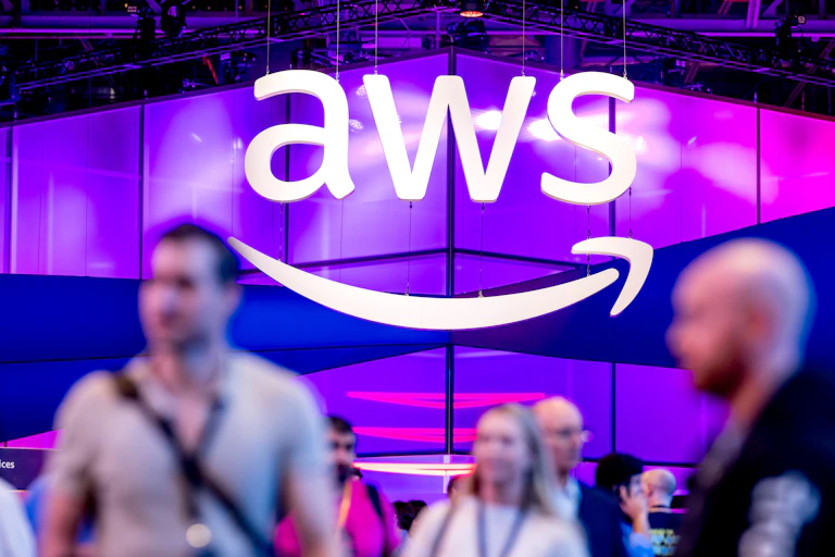 A purple exhibition stand with a white sign above it featuring the letters "AWS".