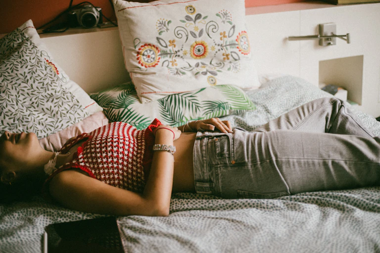 Woman lying on a bed holds her stomach.