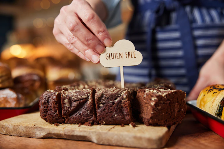 Shop or cafe assistant placing 'gluten free' label on chocolate brownies