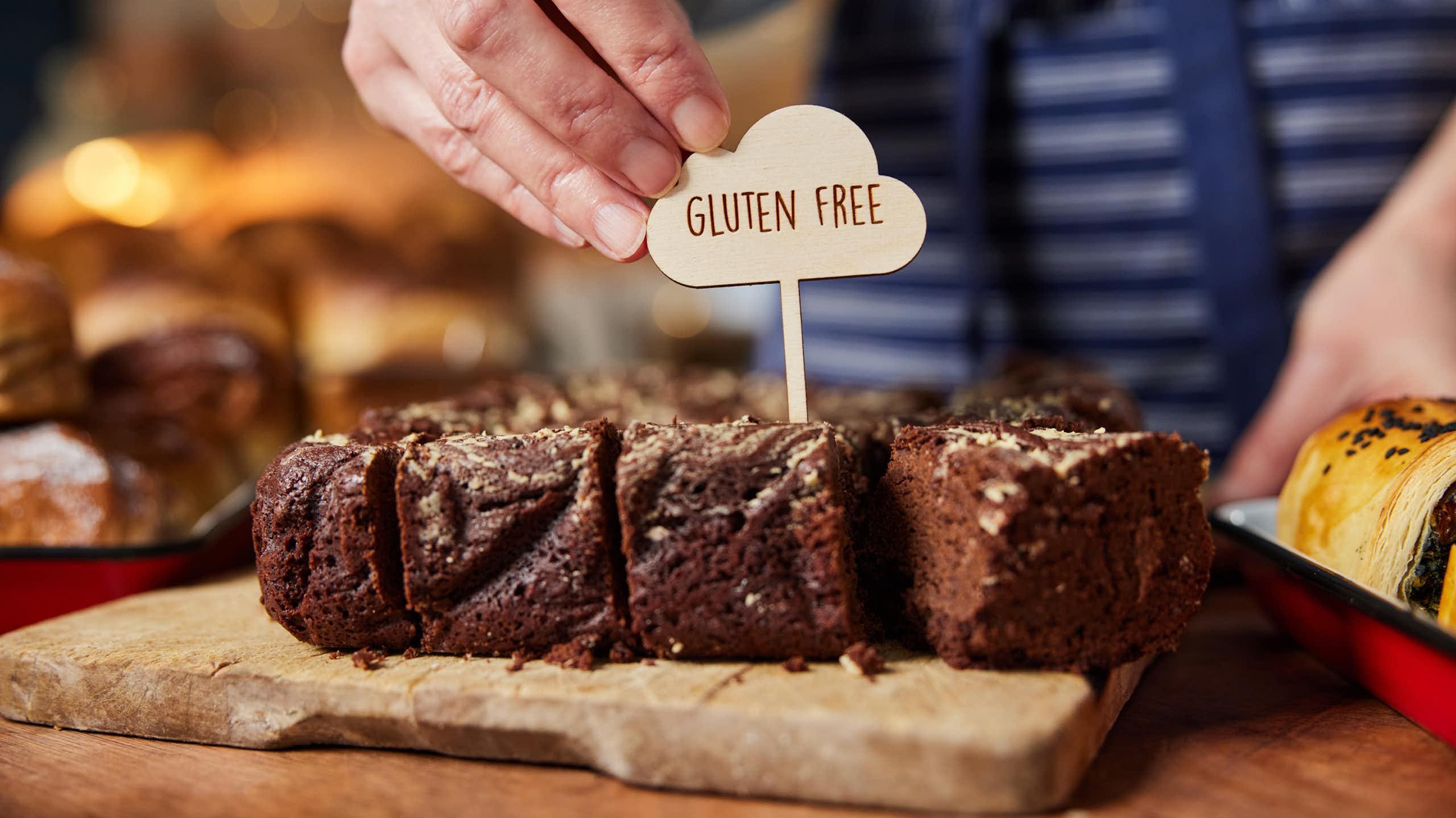 Shop or cafe assistant placing 'gluten free' label on chocolate brownies