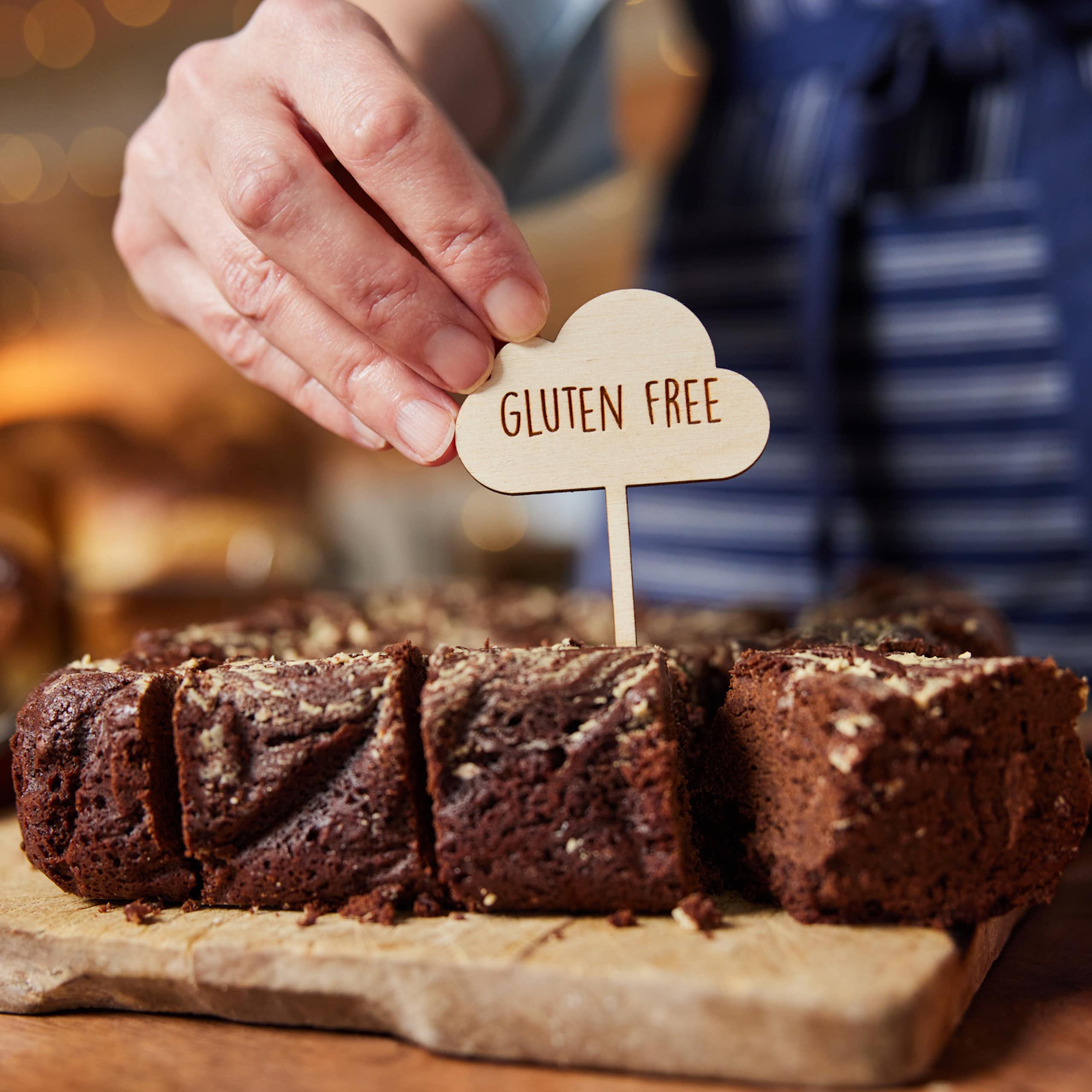 Shop or cafe assistant placing 'gluten free' label on chocolate brownies