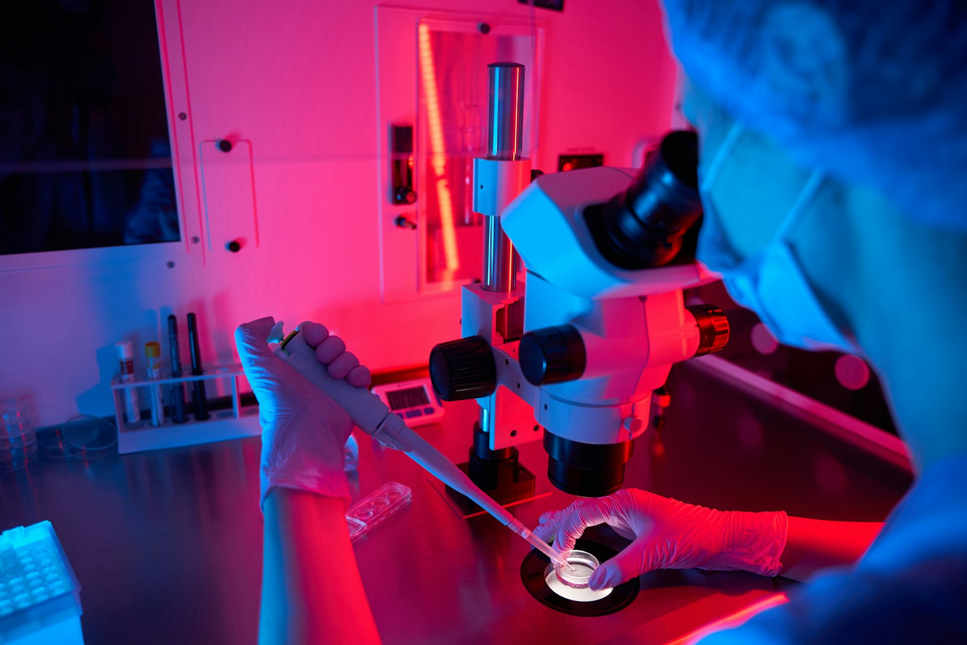 Embryologiste travaillant avec des échantillons sous un éclairage coloré.