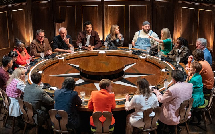 The contestants are sitting around the round table.