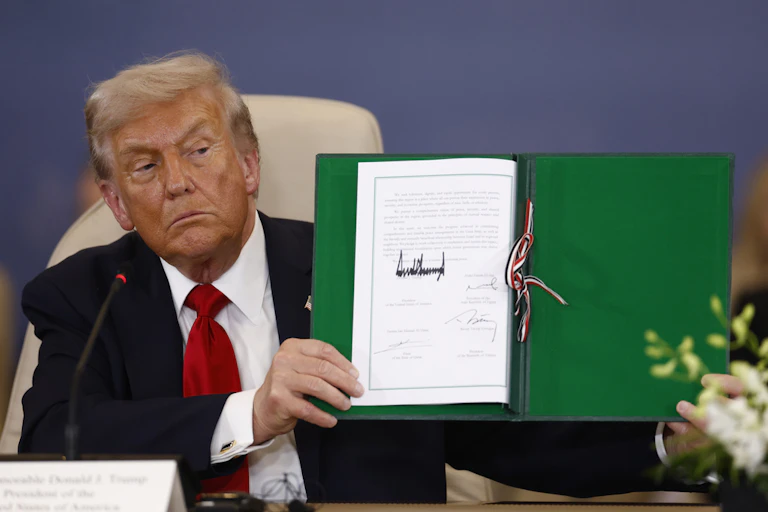 A man holds a piece of paper with a large signature.