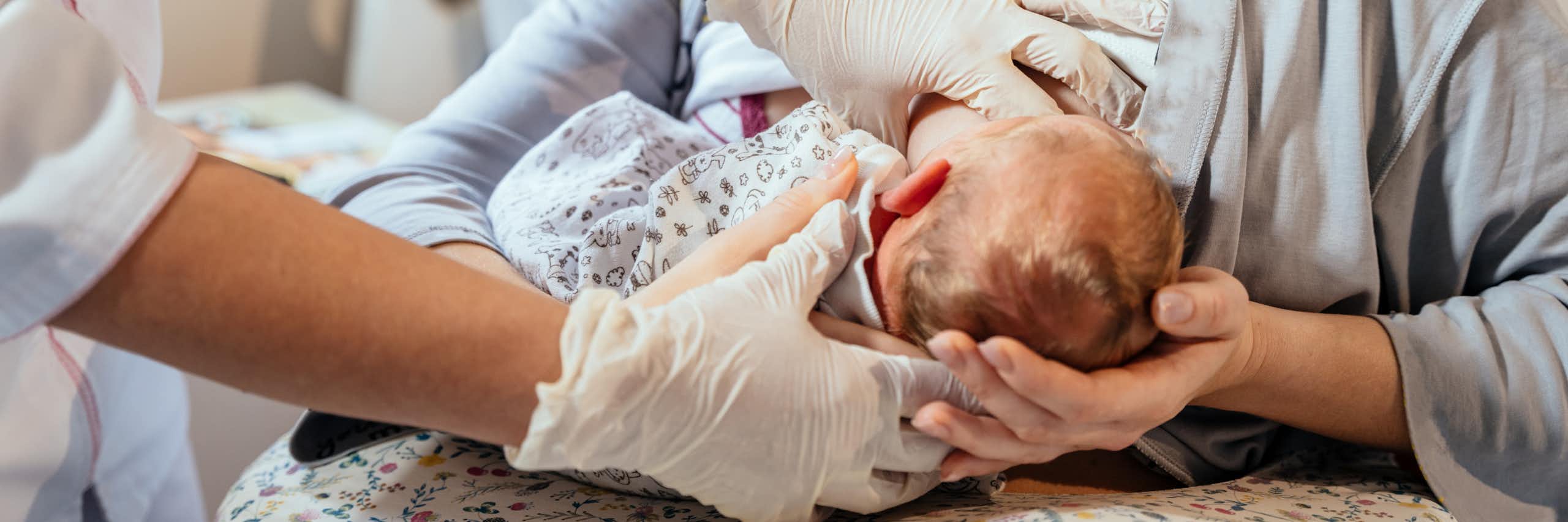 Une soignante apprend à une jeune mère à allaiter son enfant.