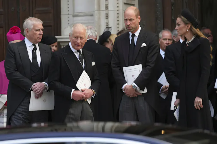 Three men and a woman dressed in black in front of a cathedral.
