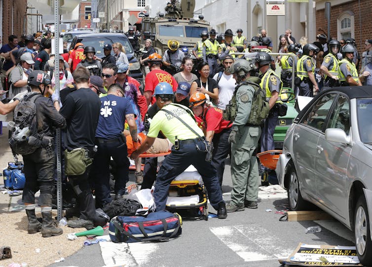 Rescue personnel working on someone on a stretcher in a street crowd