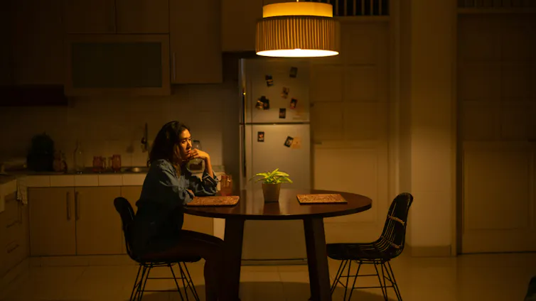 Una mujer infeliz se sienta sola en la mesa de la cocina.