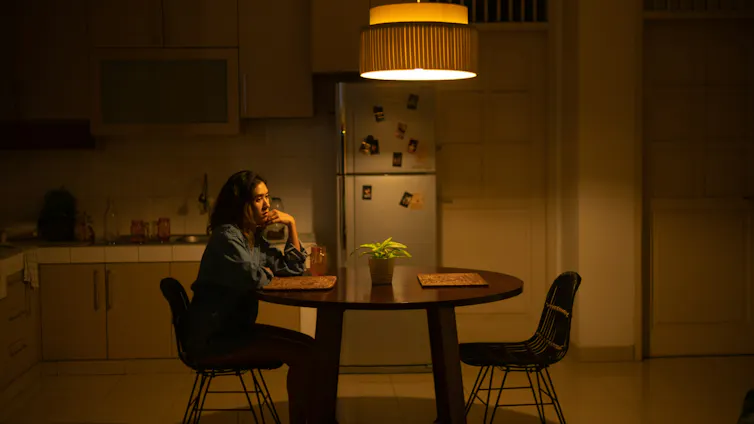 An unhappy woman sitting alone at a kitchen table