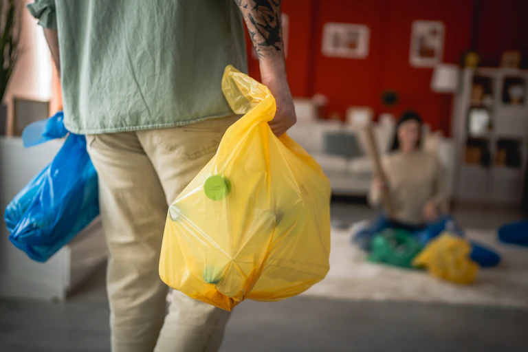 man holding recycling sacks inside home