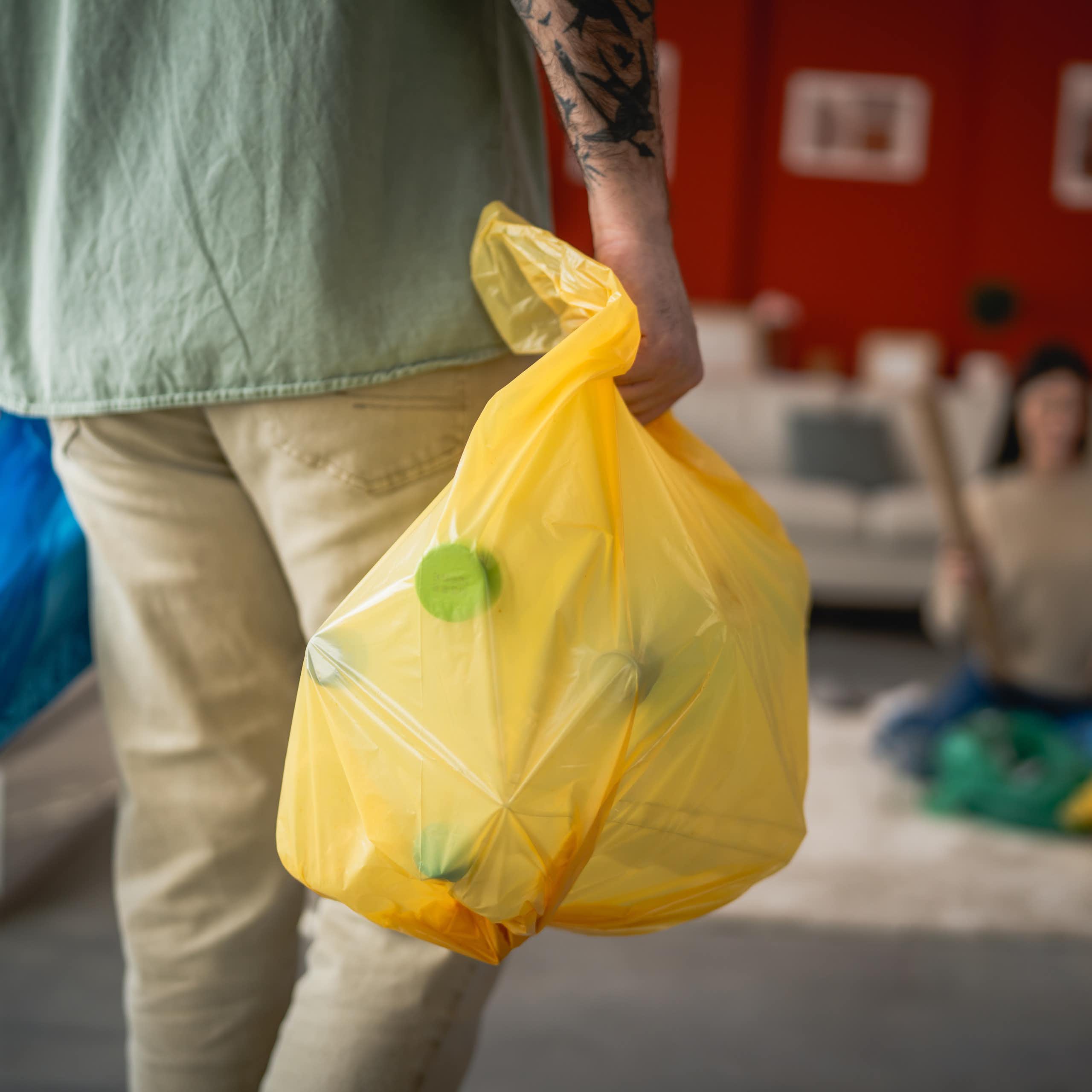 man holding recycling sacks inside home