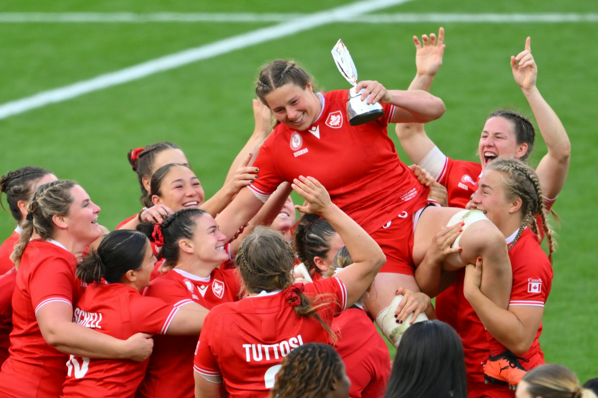 Un grupo de jugadoras de rugby recogen a una compañera de equipo para celebrarlo.