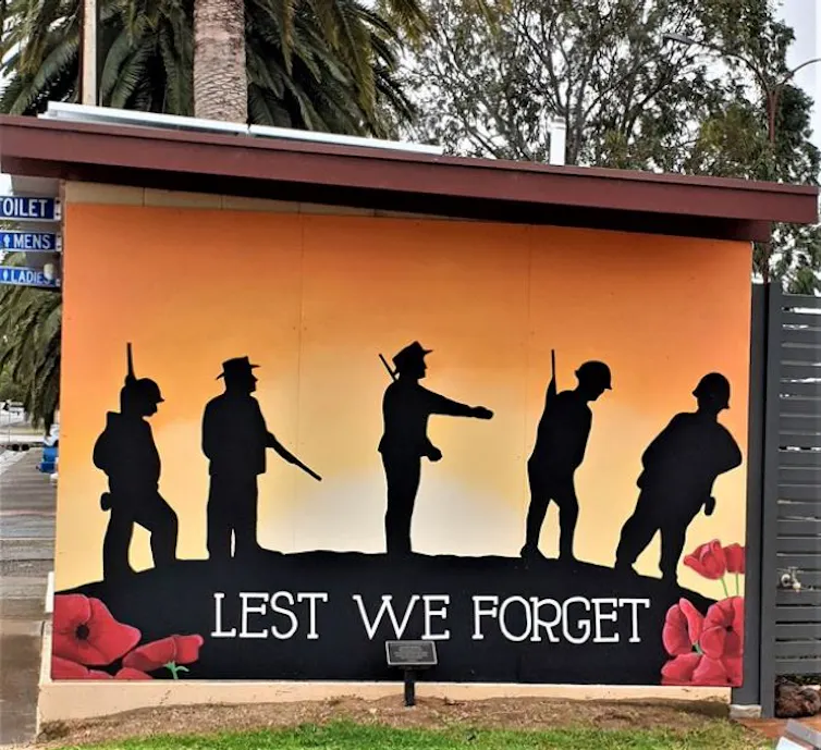 An Anzac mural is painted on a public toilet block, with the text 'LEST WE FORGET'.