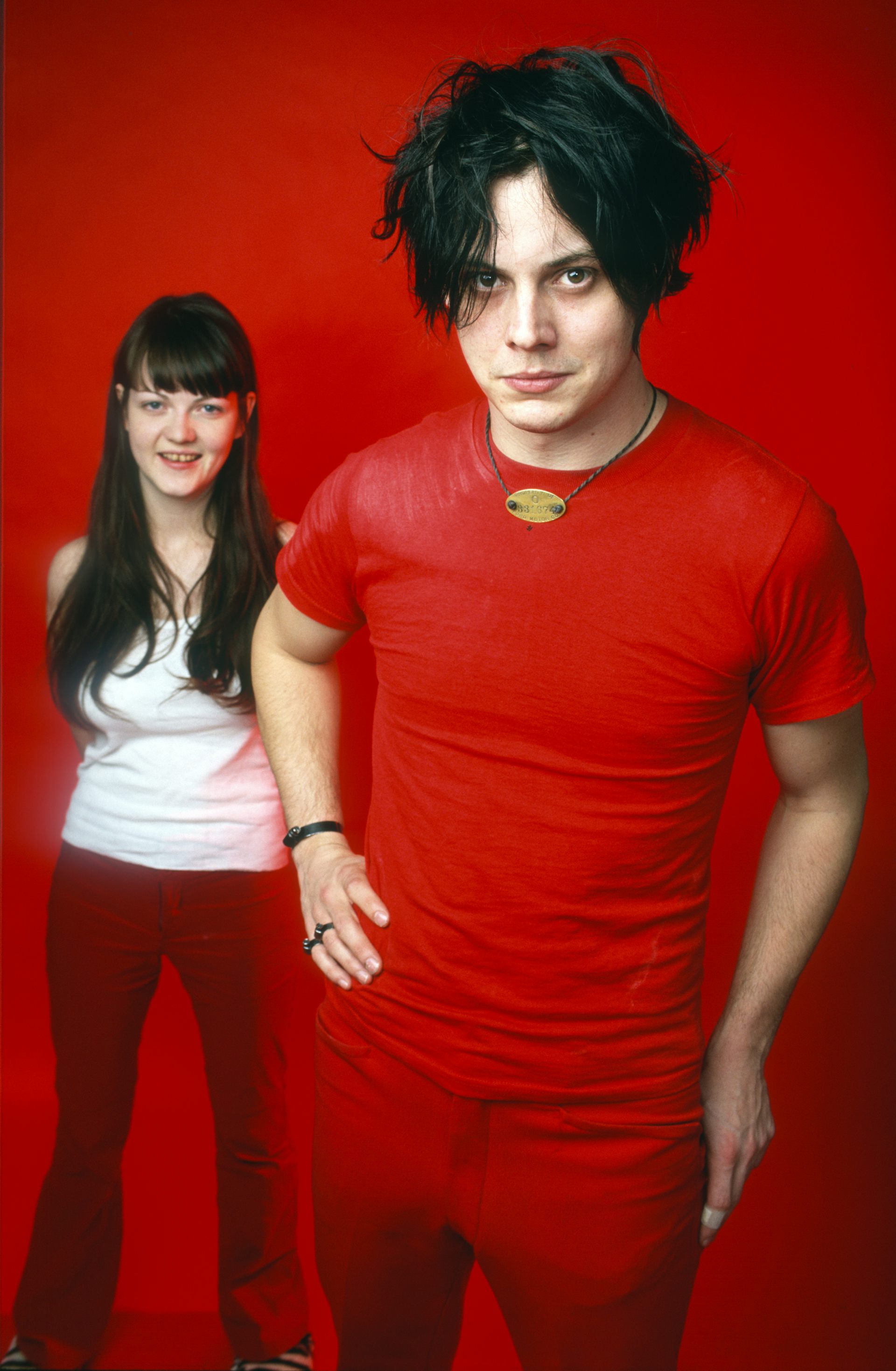 Musicians Jack White and Meg White are standing and wear red clothes