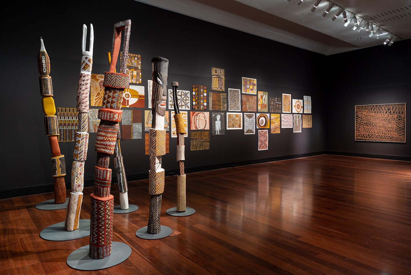 Burial poles in front of works on paper.