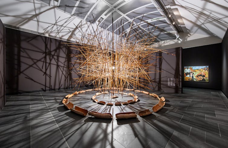 A cloud of sticks hangs in the gallery.