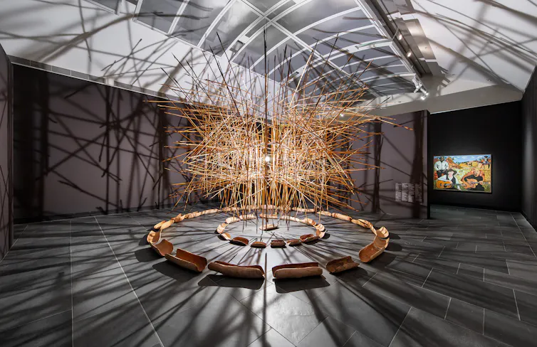 A cloud of sticks hangs in the gallery.