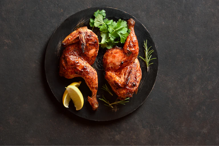 Cooked chicken on a black plate.