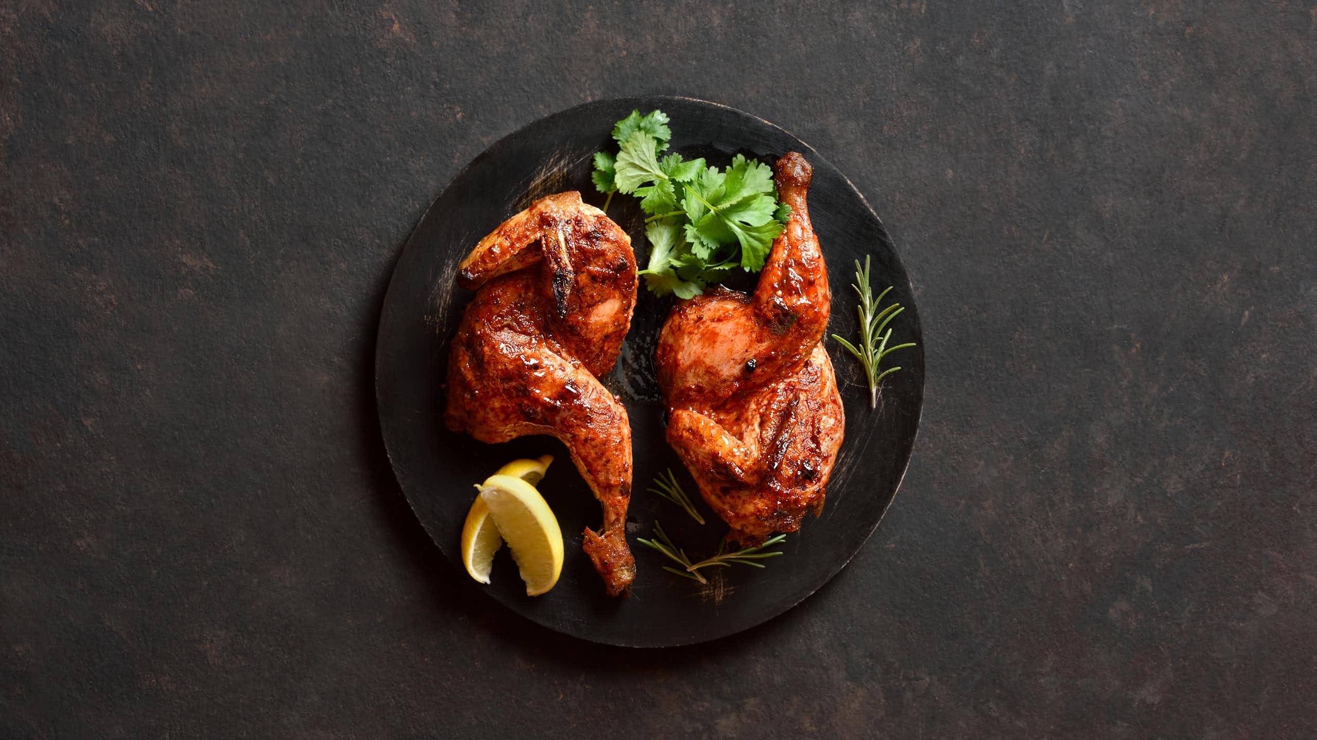 Cooked chicken on a black plate.