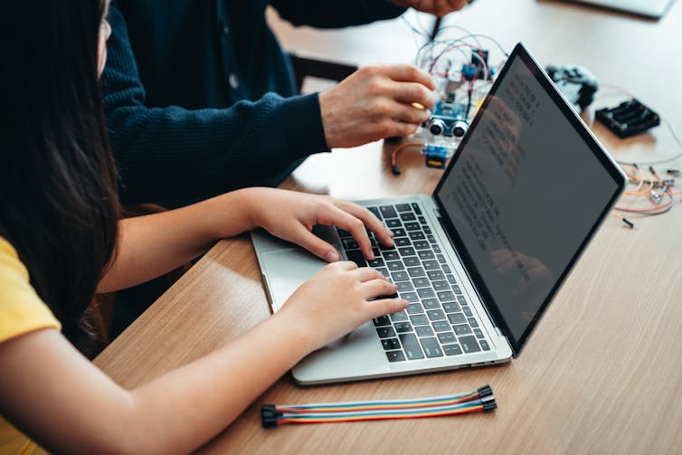 Girl with laptop and electronics tech nearby