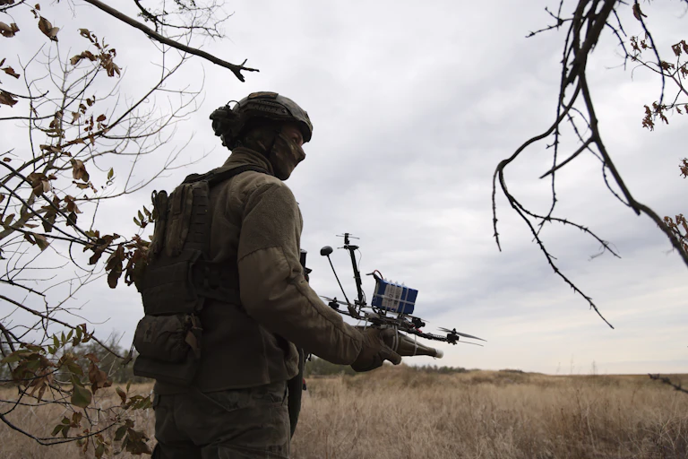 A Ukrainian soldier holds up a drone.
