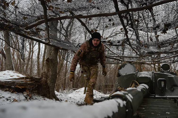 A Ukrainian serviceman at an artillery installation in the snow.