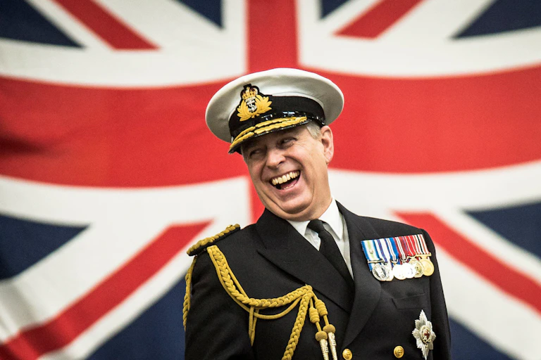 Prince Andrew laughing in front of a union flag.
